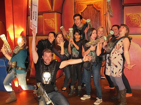 Group of coworkers playing laser tag as a teamwork game