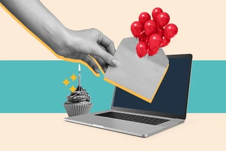 happy birthday email: image shows a cupcake next to a laptop and a hand holding an envelope with balloons attached 