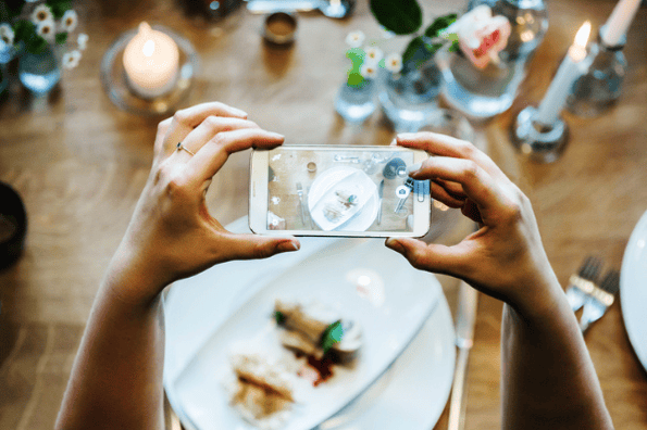 Social Media Etiquette: Woman taking a picture of her food at the table