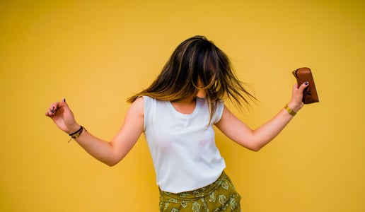 Brunette woman dancing with phone on yellow background