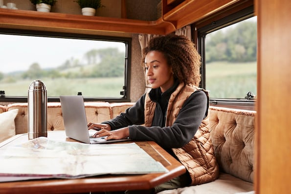 coman in a camper van using a simple website template on a laptop