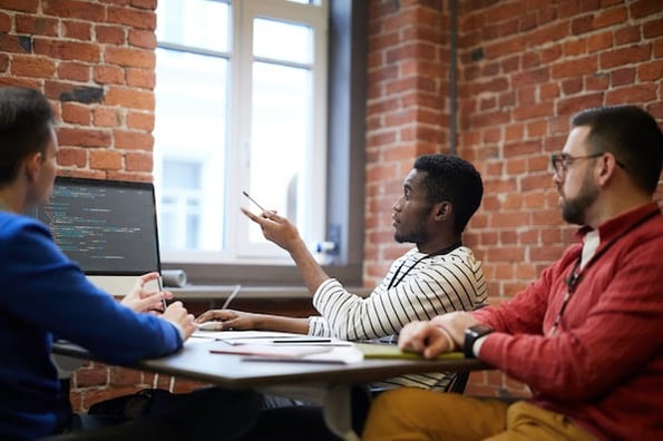 a group of people sitting at a conference table pointing at a computer screen with Google Lighthouse code on it