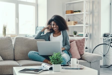 person sitting on a couch using a laptop to create responsive text with CSS