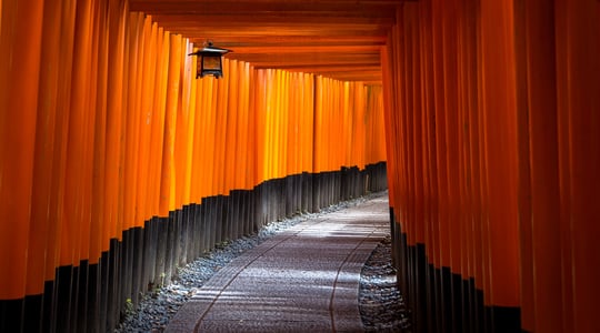 Sequence of orange, square arches, lined up one after another with a hanging lantern.