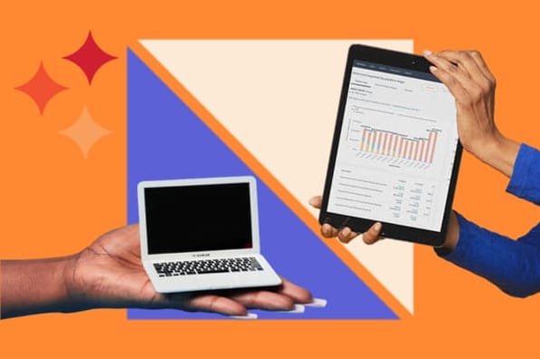 A hand holds a mini laptop and another hand holds a tablet showing web traffic