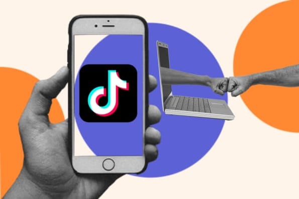 A person holds up their smartphone showing the TikTok logo 