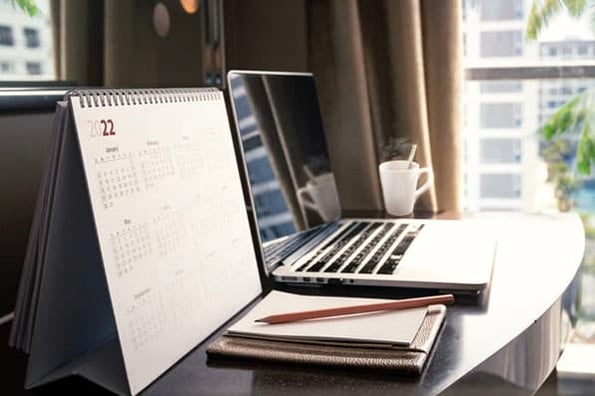 a marketer has a 2022 calendar on their desk and a notebook with our recommendations from our marketing industry trend report.