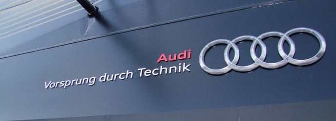 Audi's tagline, says Vorsprung durch technik, written on a black storefront