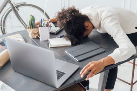 A woman slumps over her desk as she deals with burnout.