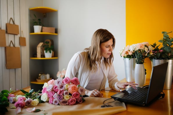 person in flower shop looking for best directory wordpress plugins on a laptop
