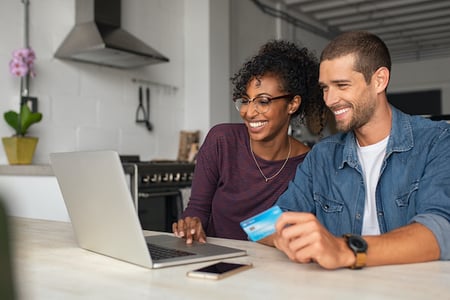 two people using a laptop and holding a credit card to complete an ecommerce checkout process