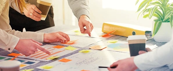 marketer in meeting pointing to sticky notes talking about client reporting tools 