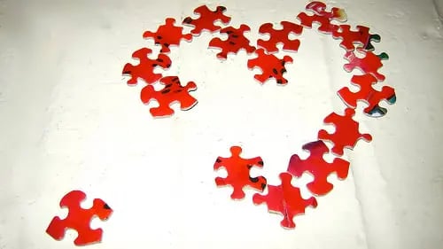 red puzzle pieces in the shape of a heart with one piece out of place