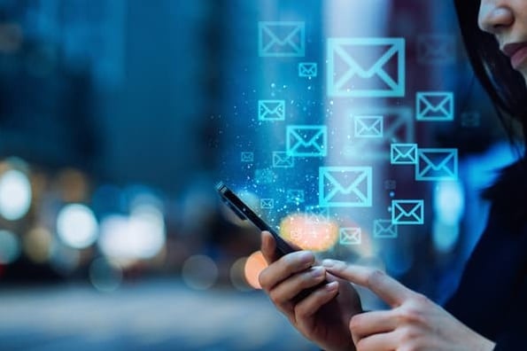 Email icons float up from a cell phone as a woman browses her email.