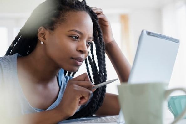 A woman holding a pen stares at her laptop as she tries to figure out if her business is on an email blacklist.