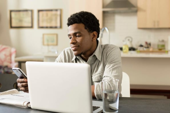 person using email management tips to clear his inbox at a kitchen table