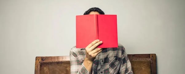 person holding book in front of face finding good data