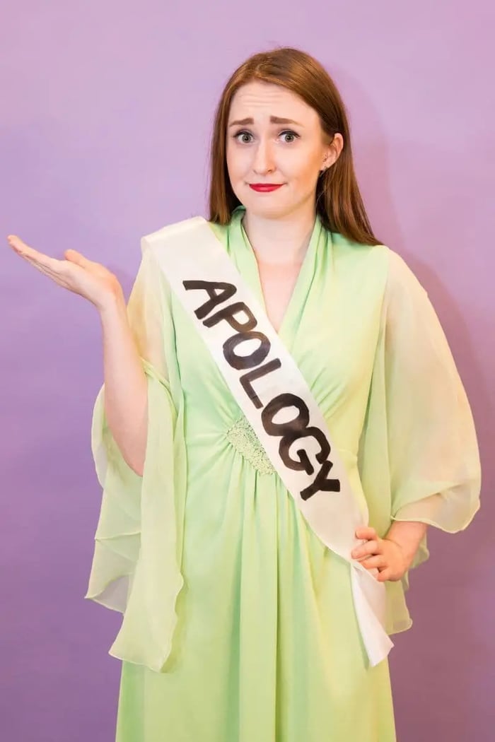 Woman wearing formal gown with a sash that says "apology."