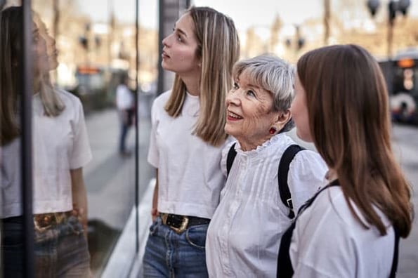 Three generations of shoppers look in a store front window at products