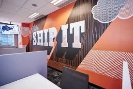 Orange mural that says 'ship it' connected a wall astatine HubSpot's Singapore office