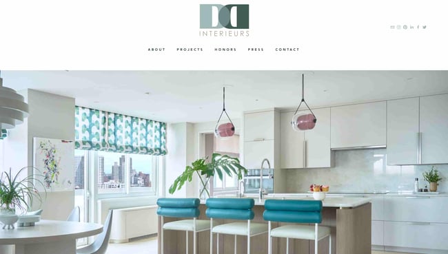interior design websites: homepage for d2 which shows an island and bright white kitchen with pops of blue. 
