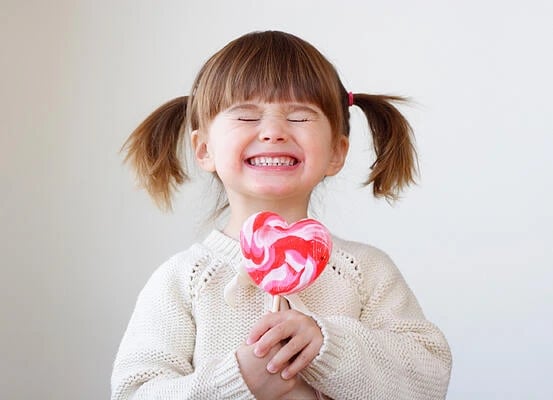 publish content for entertainment: image shows little girl with lollipop smiling