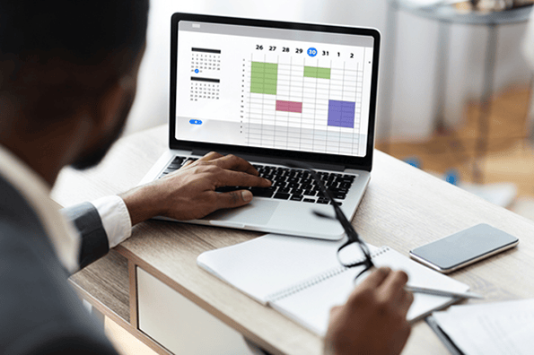 Business man trying to find a meeting time on his laptop calendar that works for everyone