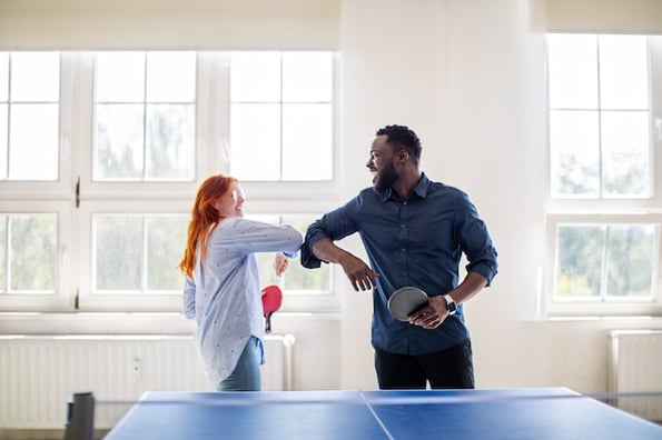two salespeople playing ping-pong at the office