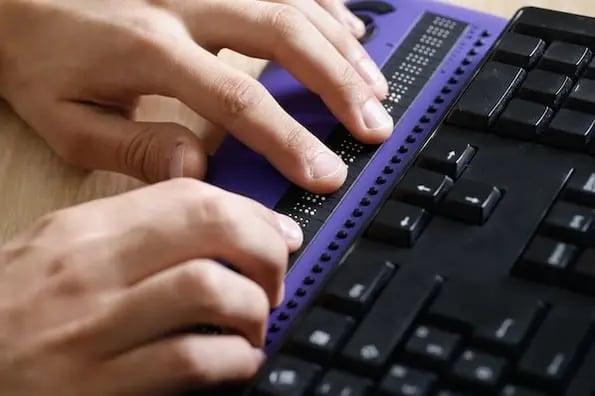 hands typing on a device to allow screen reader accessibility for a computer