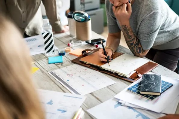 social media content calendar template: image shows people leaning over a desk talking about content calendar 