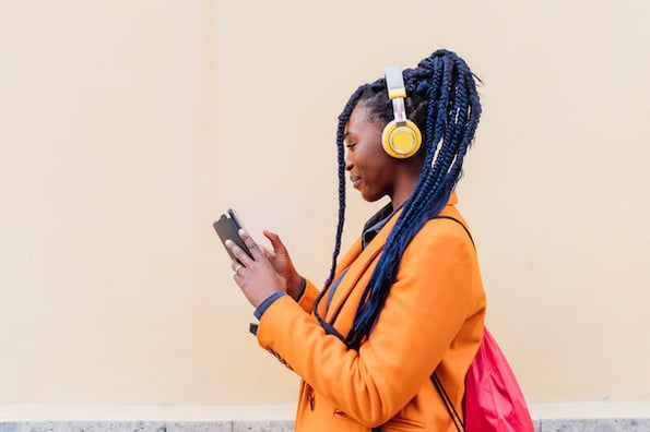 A person listens to discussion on twitter spaces using headphones and their Twitter smartphone app.