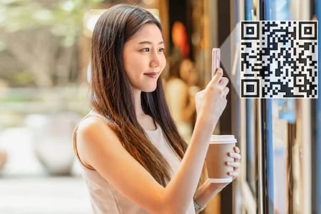 A woman scans a QR code at a coffee shop