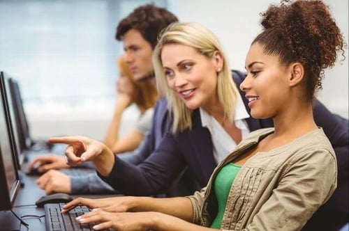 Marketing professor pointing to a student's computer screen during a lesson on alt text