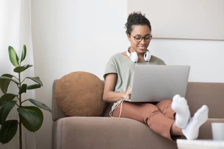 person sitting on a couch using a laptop to learn how to add wordpress plugins