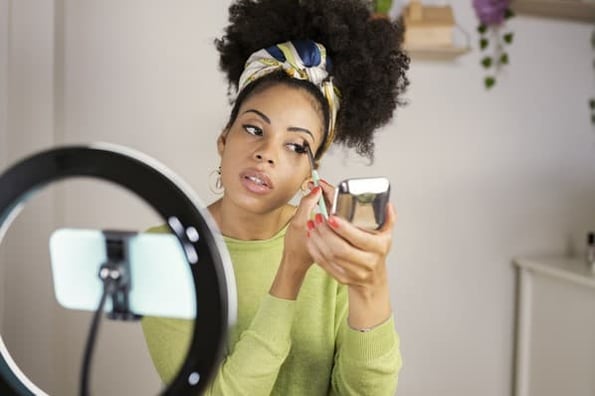 A woman films a YouTube video while applying makeup. 