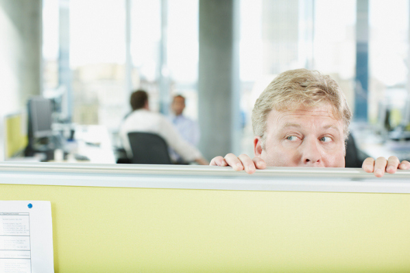 salesperson hiding behind cubicle after lying to a customer