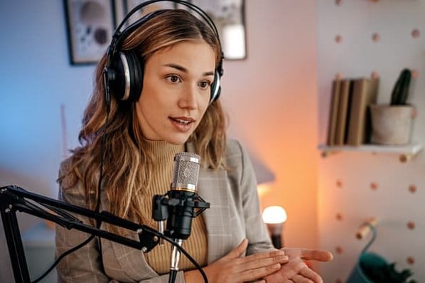 A woman records a podcast and contributes to the creator economy.
