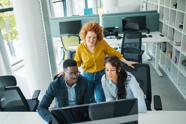 three people in an office looking at a computer and learning the difference between span and div tags