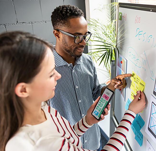 Marketers planning their SEO strategy on a white board using sticky notes and visual elements