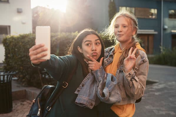 Two members of Gen Z take a selfie for social media on a smartphone.