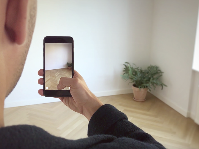 Man holding mobile device up to plant to experience IKEA Place, an AR app to visualize furniture