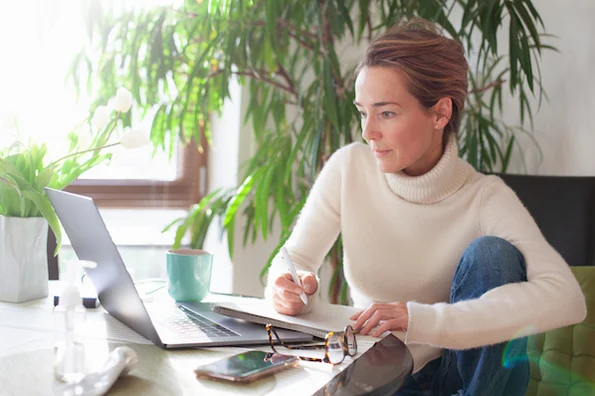woman at desk procrastinating while writing